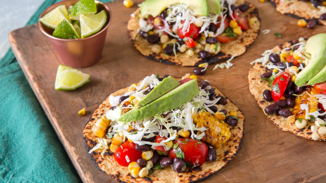 Black Bean and Corn Grilled Tostadas topped with avocado and lime wedges on the side.