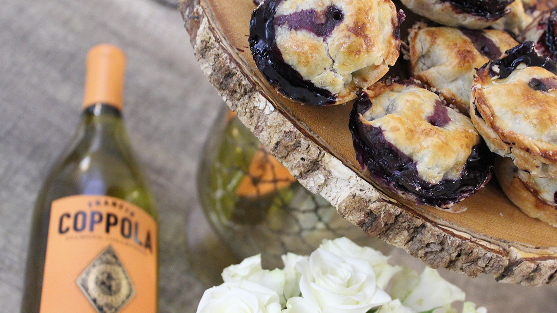 Blueberry hand pies in a stack and a bottle of Diamond Collection Chardonnay.