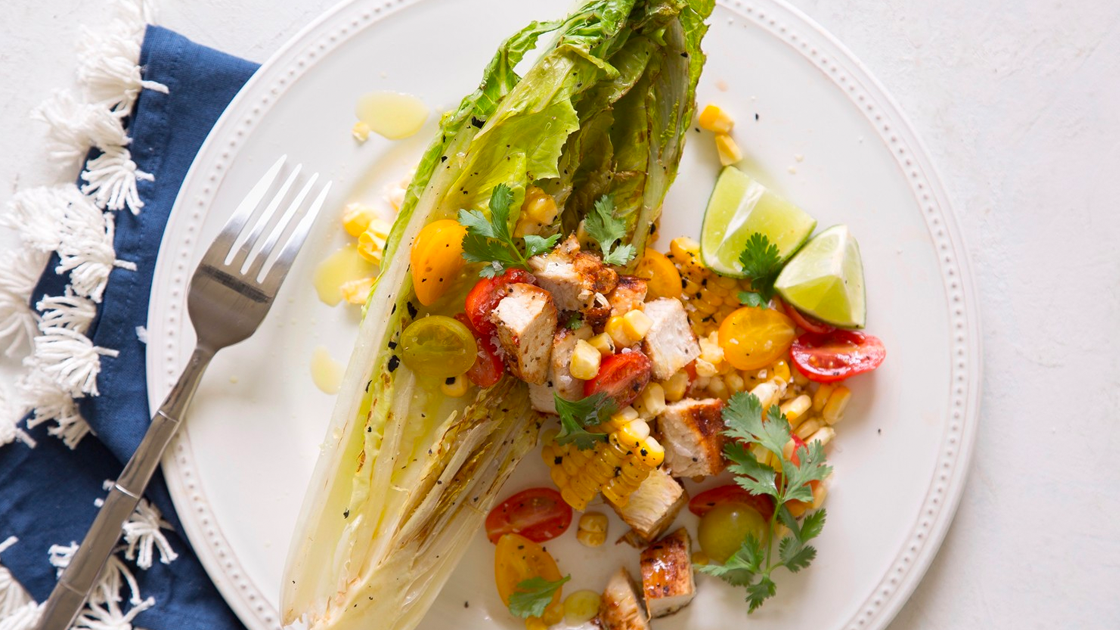 Salad topped with chicken, tomatoes, corn and lime.
