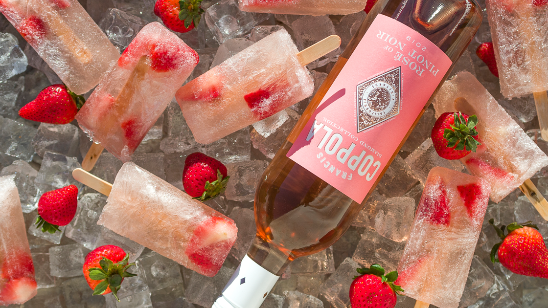 Bottle of Rosé on ice surrounded by strawberries and popsicles.