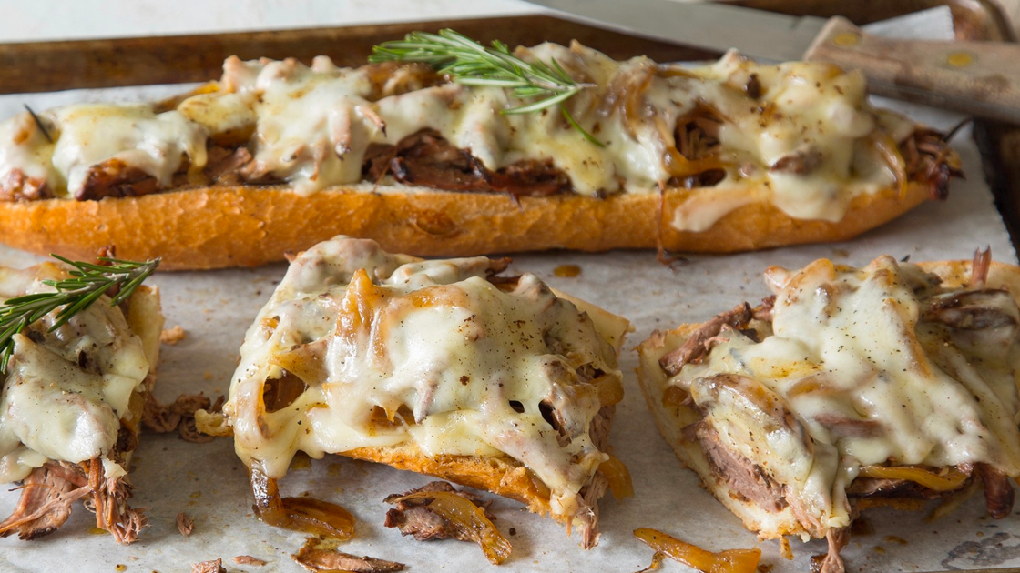 Baguette covered with shredded lamb and melted cheese, garnished with rosemary. 