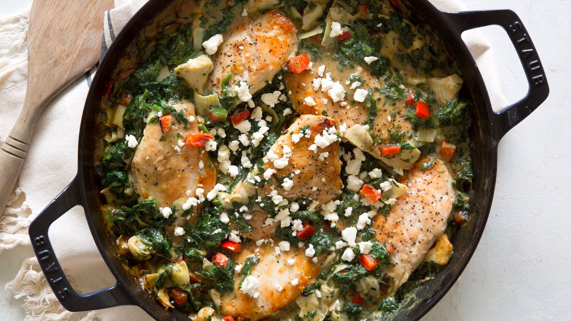 Cast Iron Skillet filled with spinach-artichoke chicken topped with feta cheese.