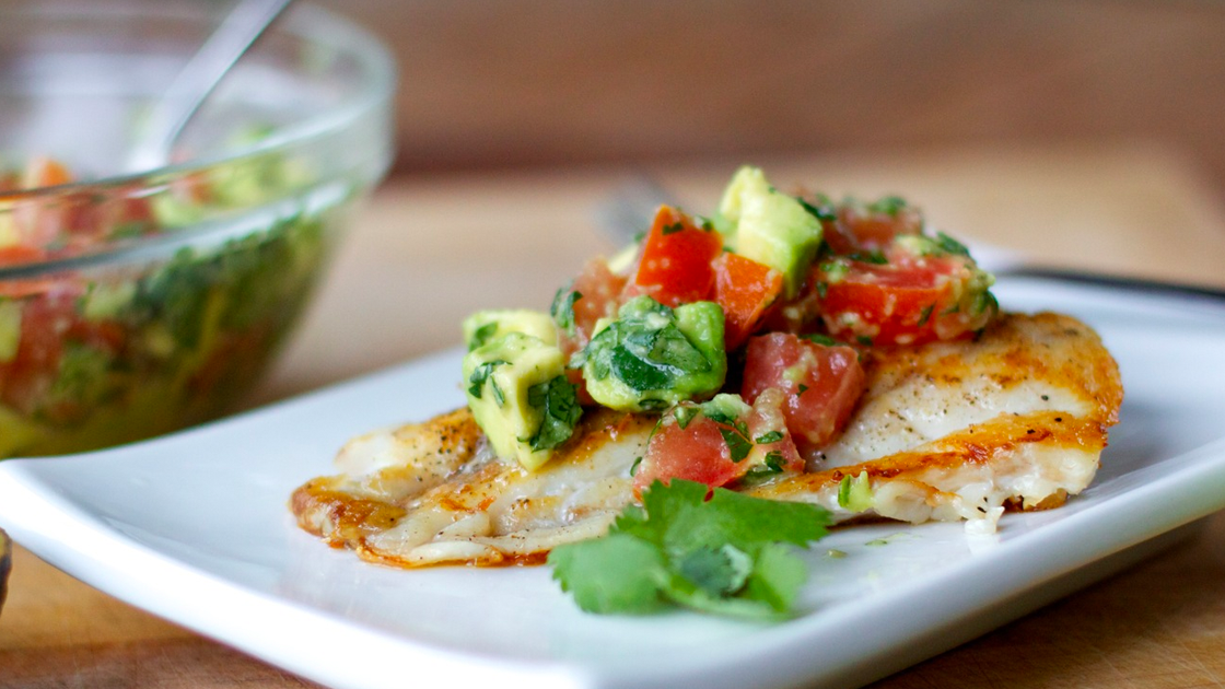 Piece of chicken topped with a tomato avocado salsa.